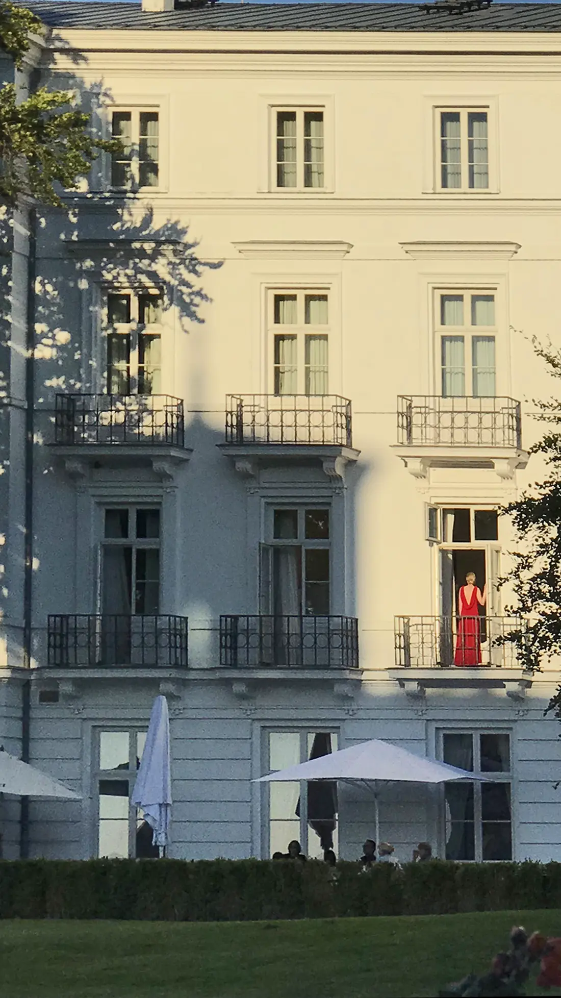 Frau in rotem Abendkleid am Hotelfenster