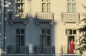 Frau in rotem Abendkleid am Hotelfenster