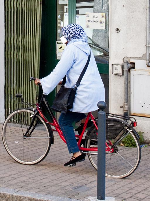 Beim Fahrradfahren wird das Handy am Ohr vom Kopftuch gehalten